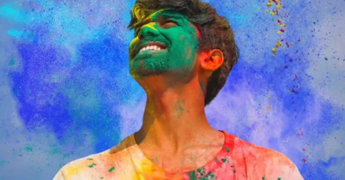 Indian man covered in colour during holi, looking up in the sky
